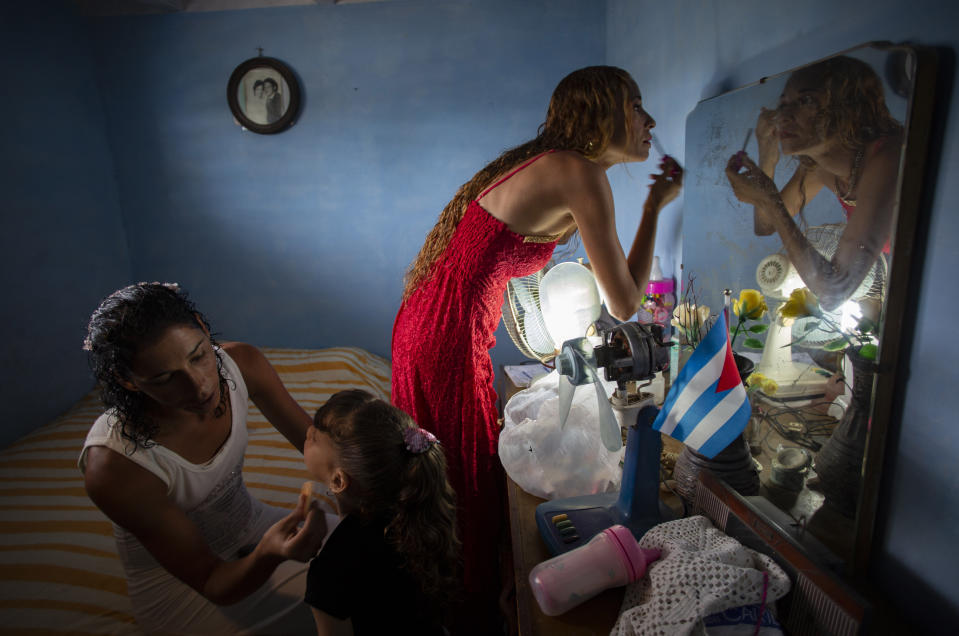 Liusba Grajales, left, puts makeup on her daughter Ainhoa as her partner Lisset Diaz Vallejo gets ready as they prepare to get married, one of the first same-sex couples to make the decision to get legally married in Cuba following the new Family Code, in Santa Clara, Cuba, on Oct. 21, 2022. (AP Photo/Ismael Francisco)