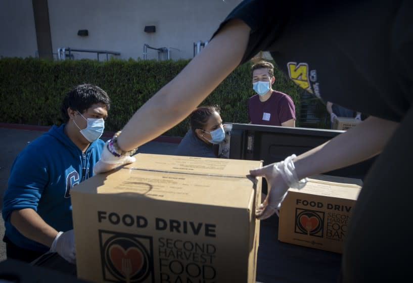 IRVINE, CA -- WEDNESDAY, APRIL 1, 2020: From left: Jose Secundino, Shavonne Budnik, Andres Quintana, and Madison Amador, who are all recently hired Second Harvest Food Bank of Orange County temporary employees, and have been laid off from restaurant jobs due to the coronavirus pandemic, load boxes of food into volunteers' trucks that will be delivered to local senior centers in Orange County. Photo taken at Second Harvest Food Bank at the Orange County Great Park in Irvine, CA, on April 1, 2020. (Allen J. Schaben / Los Angeles Times)