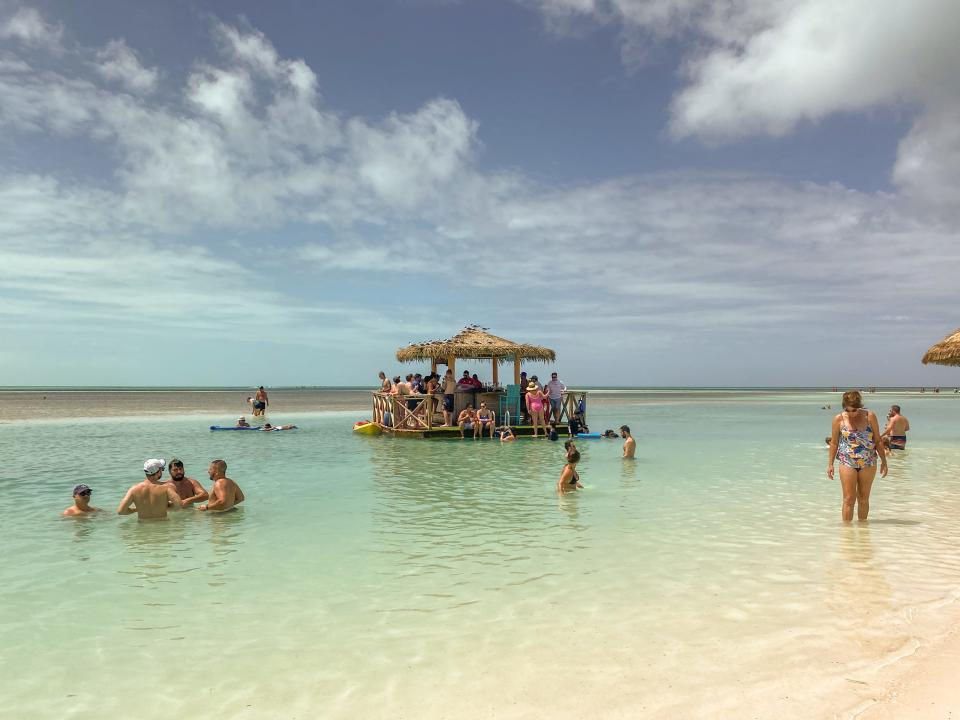 People at a swim-up bar in CocoCay in the ocean with cloudy skies in the background