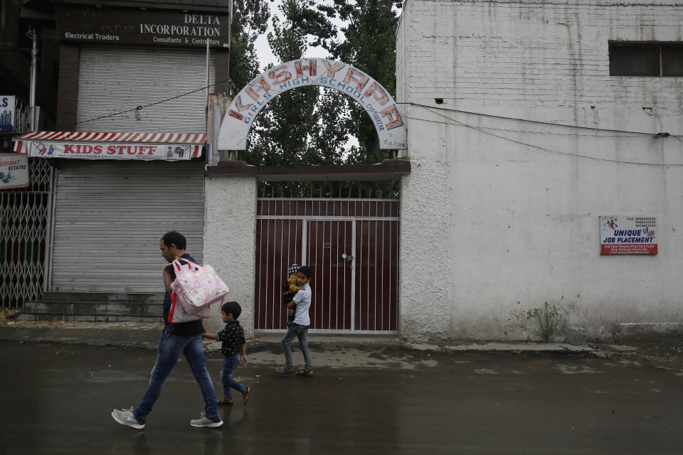 Kashmiris walk outside a closed school in Srinagar, Indian controlled Kashmir, Monday, Aug. 19, 2019. Restrictions continue in much of Indian-administered Kashmir, despite India's government saying it was gradually restoring phone lines and easing a security lockdown that's been in place for nearly two weeks. (AP Photo/Mukhtar Khan)