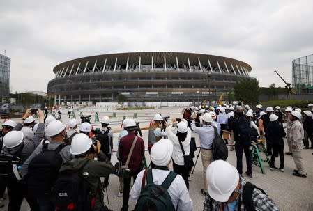 Media members are seen at the construction site of the New National Stadium, the main stadium of Tokyo 2020 Olympics and Paralympics, during a media opportunity in Tokyo