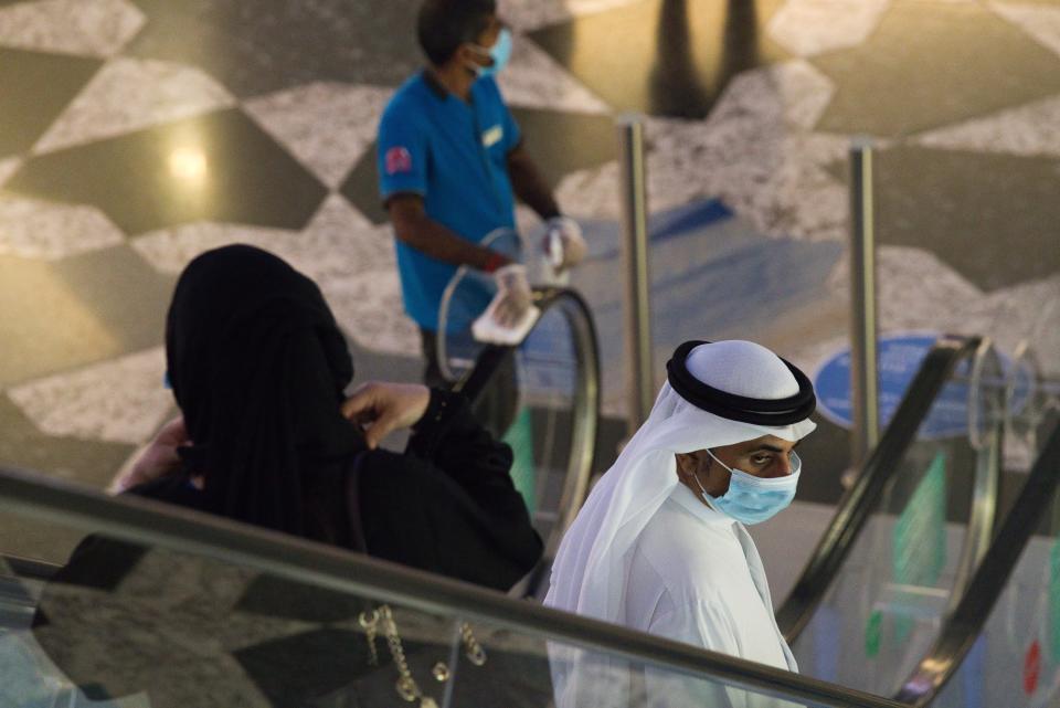 An Emirati man and woman ride an escalator at Mall of the Emirates in Dubai, United Arab Emirates, Wednesday, May 27, 2020. Dubai on Wednesday loosed its restrictions imposed over the coronavirus pandemic, allowing movie theaters and other attractions to operate. (AP Photo/Jon Gambrell)