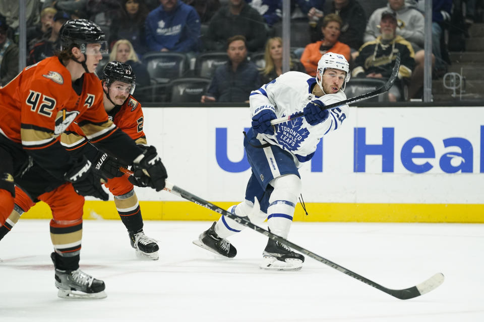 Toronto Maple Leafs' Michael Bunting, center, shoots under pressure by Anaheim Ducks' Josh Manson, left, and Sam Steel during the first period of an NHL hockey game Sunday, Nov. 28, 2021, in Anaheim, Calif. (AP Photo/Jae C. Hong)