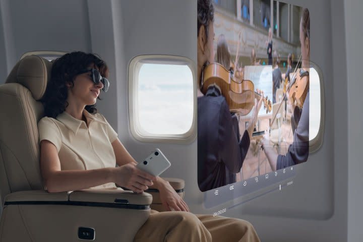 A person on a plane watches a giant virtual screen with Xreal Air 2 and Beam Pro.