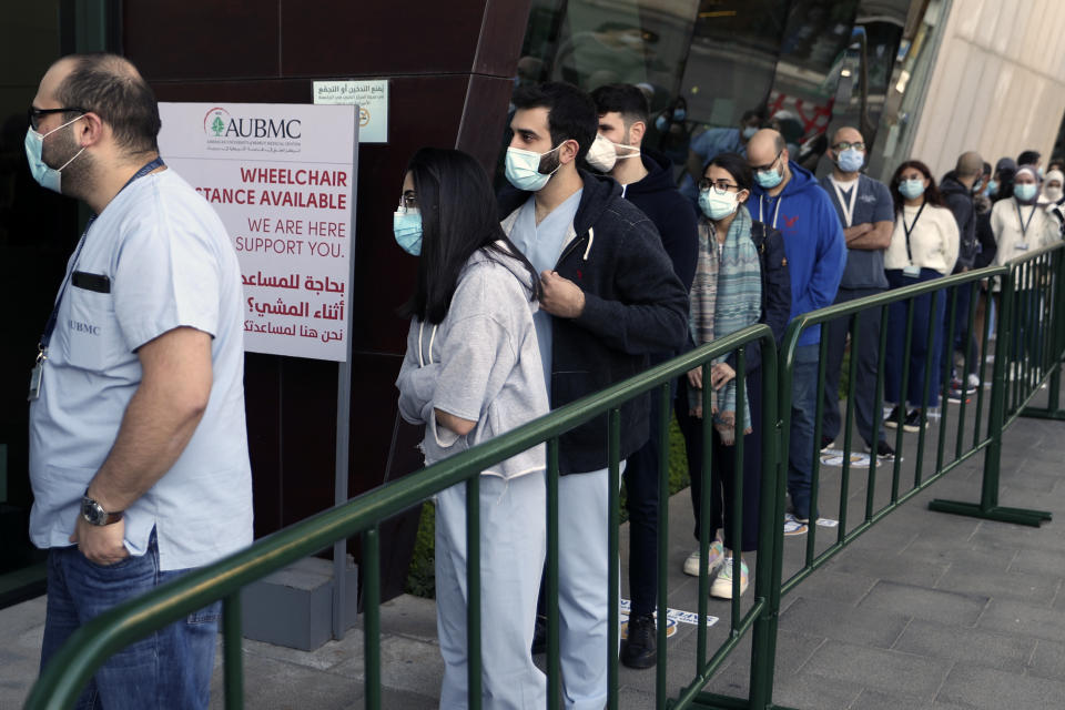 Frontline medical workers stand in line to get the Pfizer-BioNTech COVID-19 vaccine during a nationwide vaccination program at the American University Medical Center in Beirut, Lebanon, Sunday, Feb. 14, 2021. (AP Photo/Bilal Hussein)