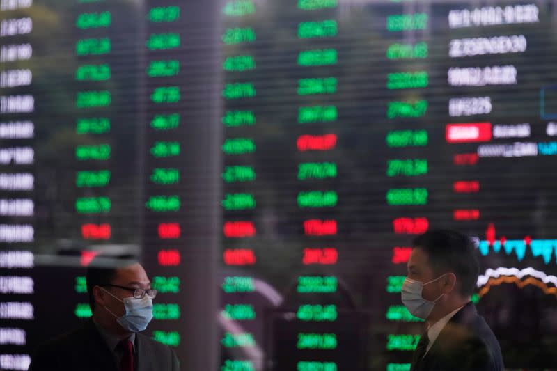 FILE PHOTO: Men wearing face masks are seen inside the Shanghai Stock Exchange building, as the country is hit by a novel coronavirus outbreak, at the Pudong financial district in Shanghai