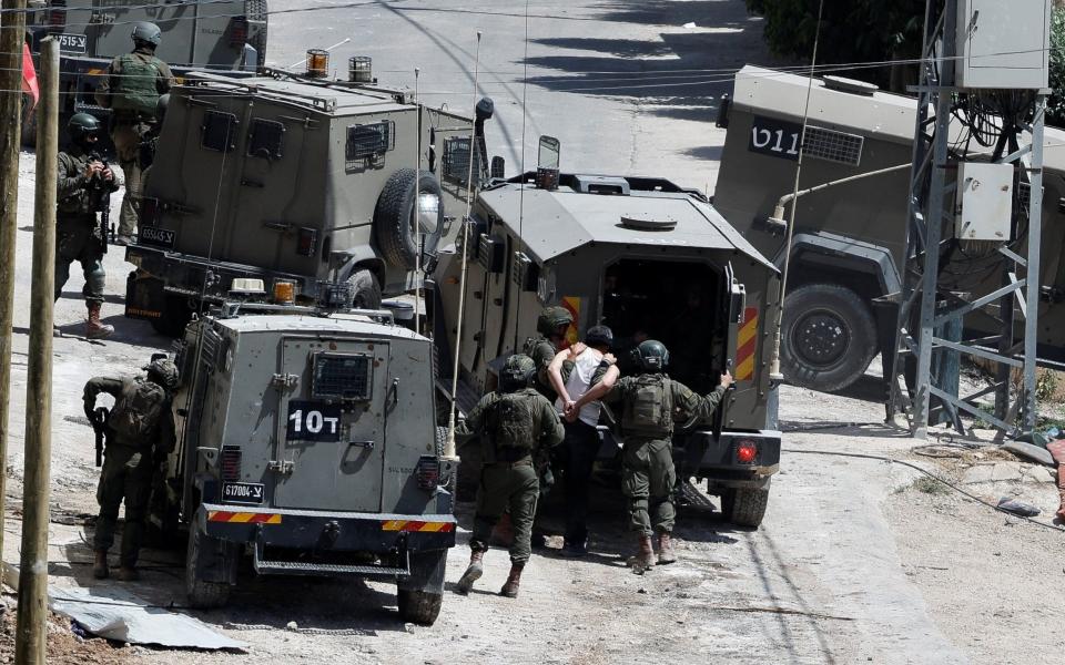 Israeli soldiers detain a man near a military vehicle during an Israeli raid in Deir al-Ghusun, in the Israeli occupied West Bank, May 4, 2024.