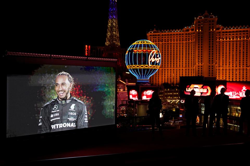 People watch as a recording of Mercedes driver Lewis Hamilton is projected onto a screen during a news conference announcing a 2023 Formula One Grand Prix race to be held in Las Vegas.