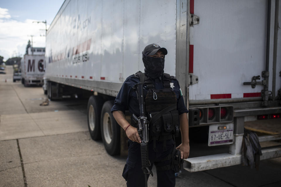 A state police officer stands guard by a cargo truck at the Attorney Generals Office after it was intercepted carrying migrants on the highway, in Coatzacoalcos, Veracruz state, Mexico, Friday, Nov. 19, 2021. About 500 migrants were riding in two cargo trucks when they were stopped and detained by the Criminal Investigation Agency and the National Immigration Institute, according to those two organizations. (AP Photo/Felix Marquez)