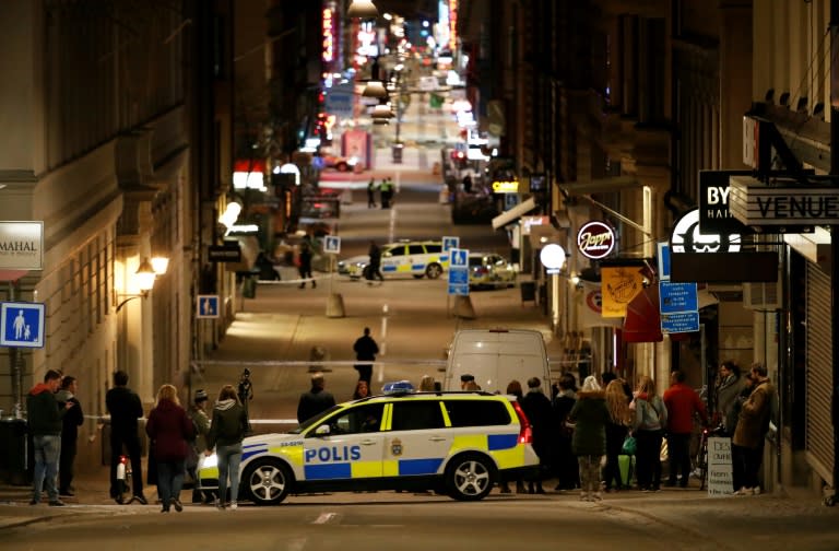 People stand behind a cordon as police work at the scene of a truck attack that killed four people outside a busy department store in central Stockholm on April 7, 2017