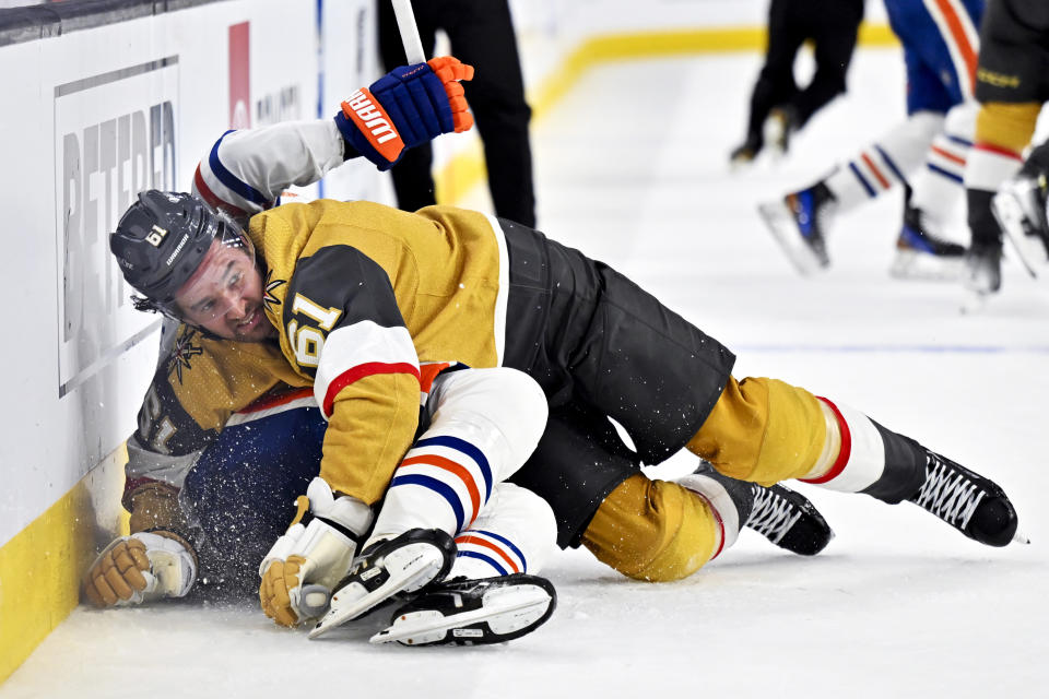 Vegas Golden Knights right wing Mark Stone (61) knocks Edmonton Oilers center Leon Draisaitl (29) to the ice during the first period of an NHL hockey game Tuesday, Feb. 6, 2024, in Las Vegas. (AP Photo/David Becker)