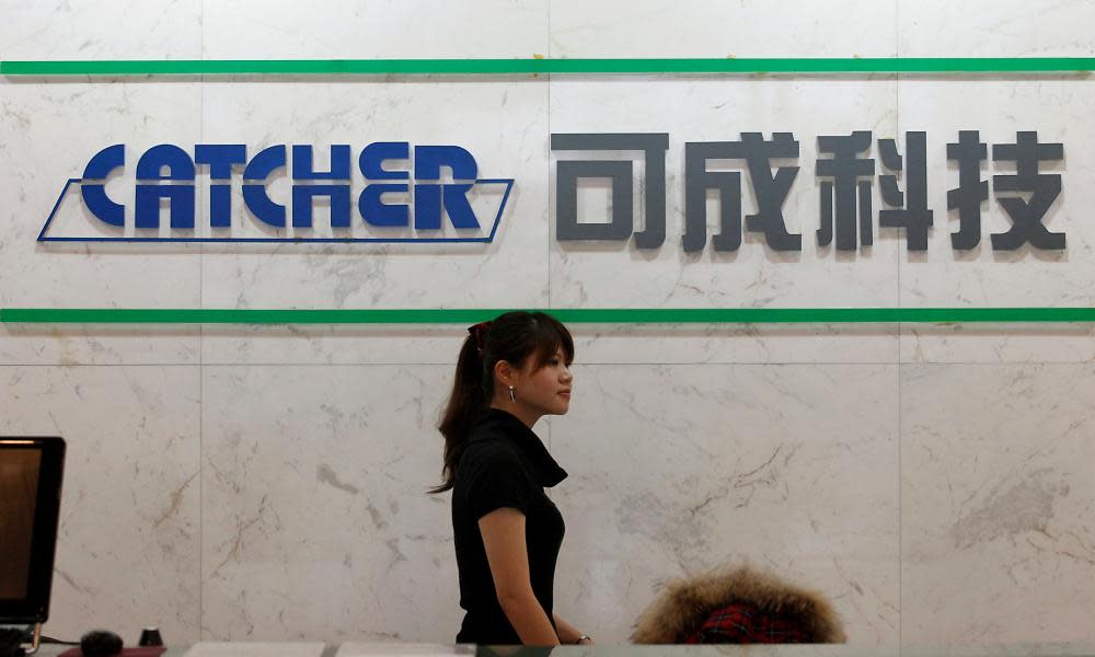 Employee walks past a logo of Catcher Technology at the company’s headquarters in Tainan, southern Taiwan.