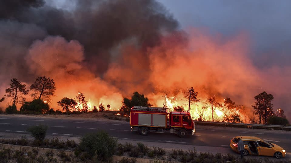 A fire truck moves along a road as a forest fire rages near the town of Melloula in northwestern Tunisia on July 24. - Fethi Belaid/AFP/Getty Images