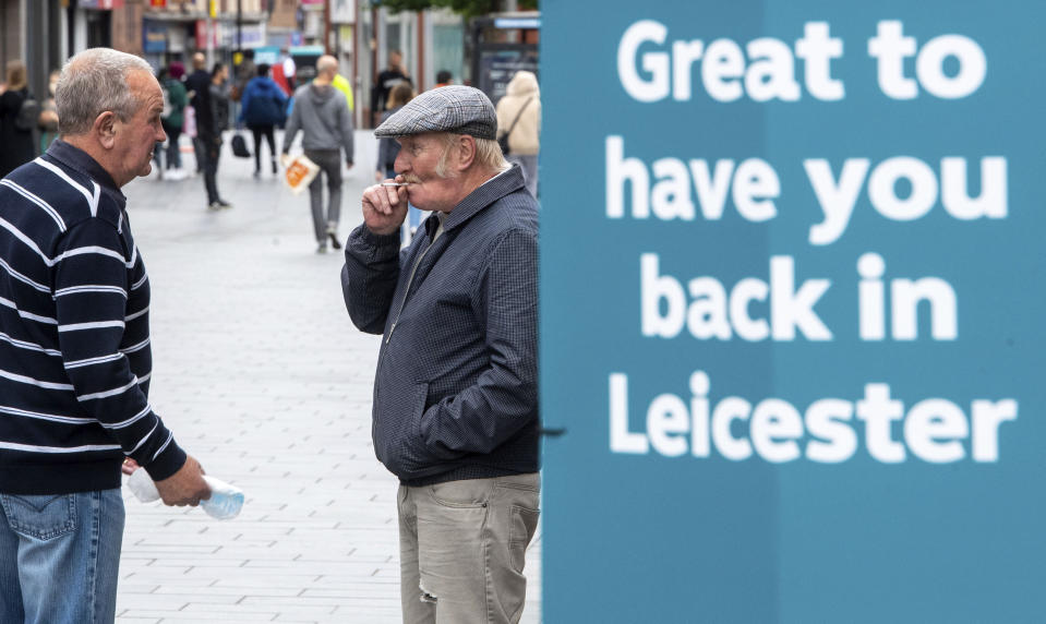 Two men have a discussion next to a sign in central Leicester, England, Monday June 29, 2020. The British government is reimposing lockdown restrictions in the central England city of Leicester after a spike in coronavirus infections, including the closure of shops that don’t sell essential goods and schools. (Joe Giddens/PA via AP)