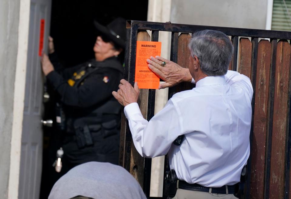 Arrowhead Precinct constable Michael Branham and constable Darlene Martinez post eviction stickers on entrances to a resident's home near downtown Phoenix area Oct. 20, 2021.