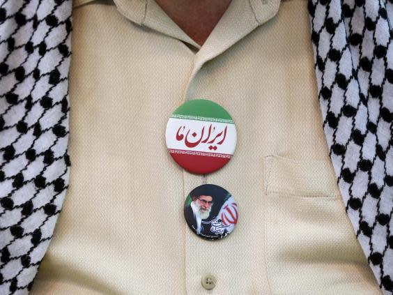 An Iranian man wears a badge of the supreme leader at Friday prayers (EPA)