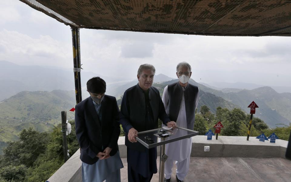 Pakistan's Foreign Minister Shah Mahmood Qureshi, middle, talks to media as Defense Minister Pervez Khattak, right, and Moeed Yusuf, the National Security Advisor to the Prime Minister of Pakistan, stand next to him, during their visit to forward area post along a highly militarized frontier in the disputed region of Kashmir, in Chiri Kot sector, Pakistan, Monday, Aug. 3, 2020. The region's top Pakistani military commander briefed ministers about Indian cease-fire violations in Kashmir, which is split between Pakistan and India and claimed by both in its entirety. (AP Photo/Anjum Naveed)