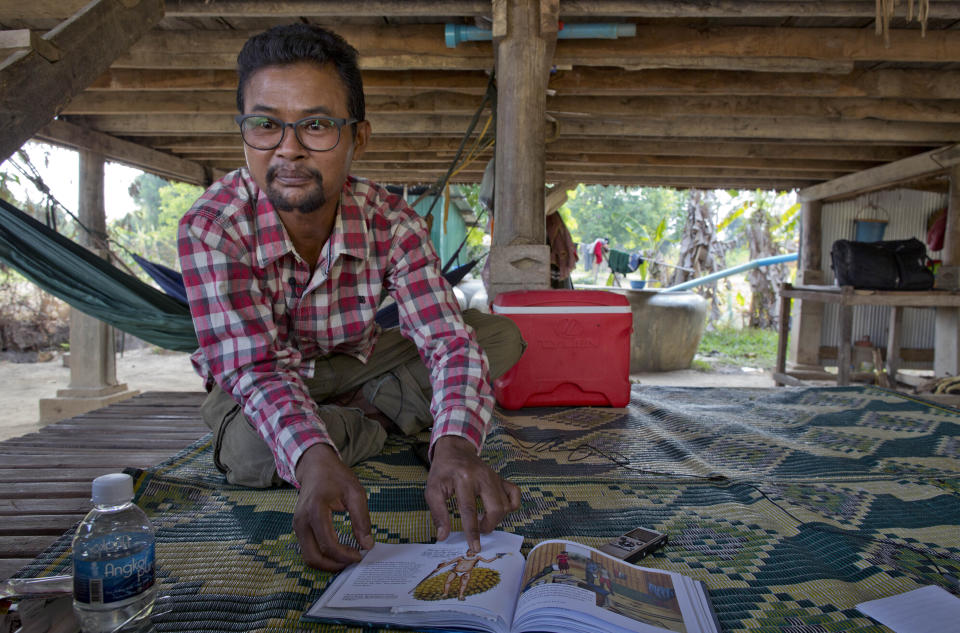 Vannak Anan Prum, who was double trafficked, points to his illustration of an abusive former boss, a palm oil estate owner, in his graphic novel depicting his life as a slave on a fishing boat before being sold onto a Malaysian palm oil plantation, at his home in Pursat, Cambodia, Saturday, March 30, 2019. (AP Photo/Gemunu Amarasinghe)