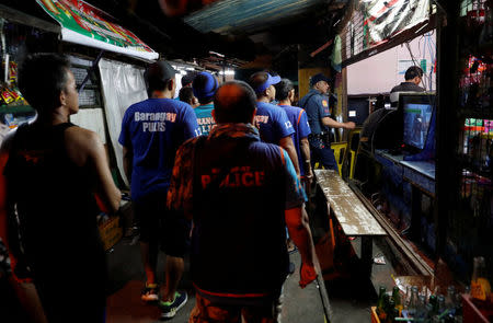 Policemen and Barangay watchmen patrol an alley as they look for teenagers lingering in the streets in Tondo, Manila, Philippines July 2, 2018. REUTERS/Erik De Castro/Files