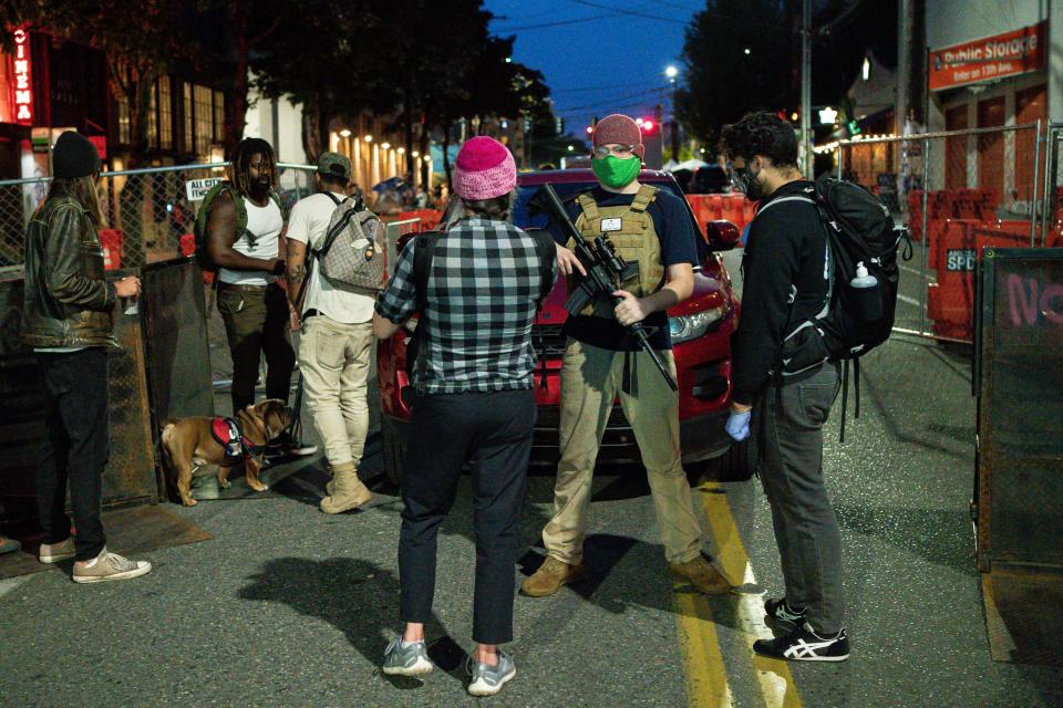 A volunteer holds a firearm while working security at an entrance to the so-called "Capitol Hill Autonomous Zone" on June 10, 2020, in Seattle, Washington. The zone includes the blocks surrounding the Seattle Police Department's East Precinct, which was the site of violent clashes with Black Lives Matter protesters.