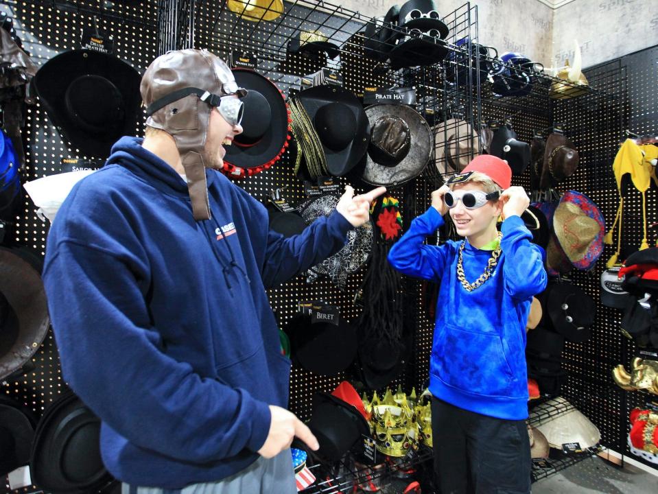 A man and young boy try on hats and glasses at a Spirit Halloween store.