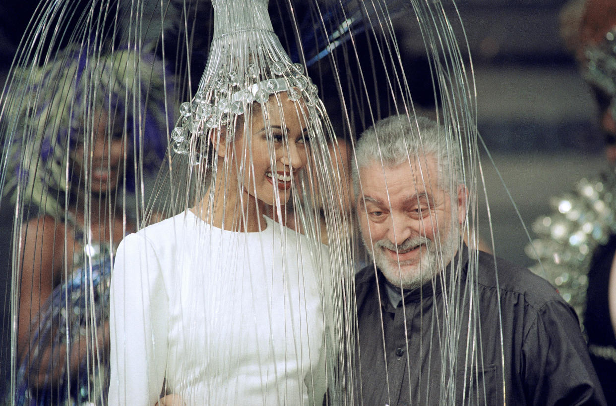 FILE - Spanish fashion designer Paco Rabanne poses with a model wearing a white dress with a metallic headpiece after presenting his 1992/93 fall-winter haute couture collection in Paris, France, on July 29, 1992. The Spanish-born pace-setting designer known for perfumes sold worldwide and his metallic, space-age fashions, has died, the group that owns his fashion house announced on its website Friday Feb.3, 2023. He was 88. (AP Photo/Laurent Rebours, File)