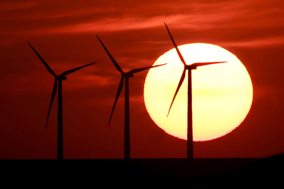 Wind turbines silhouetted against the setting sun as they produce electricity near Beaumont, Kansas.