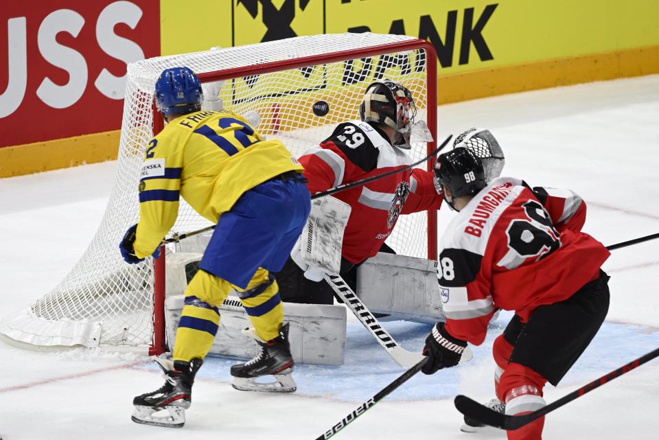 Max Friberg of Sweden, left, scores past goalkeeper Bernhard Starkbaum of Austra, during the 2022 IIHF Ice Hockey World Championships preliminary round group B match between Sweden and Austria, in Tampere, Finland, Saturday, May 14, 2022. (Emmi Korhonen/Lehtikuva via AP)