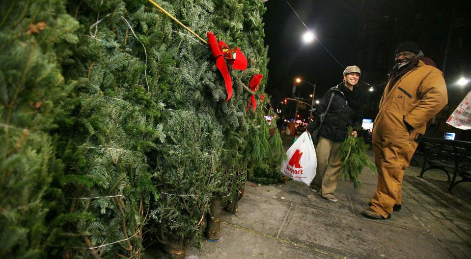 NEW YORK, NY – DECEMBER 17: People gather as Christmas trees are seen for sale December 17, 2010 in the Manhattan borough of New York City. Retailers across the country are hopeful for a rebound in Christmas-related sales as the economy slowly improves. (Photo by Mario Tama/Getty Images)