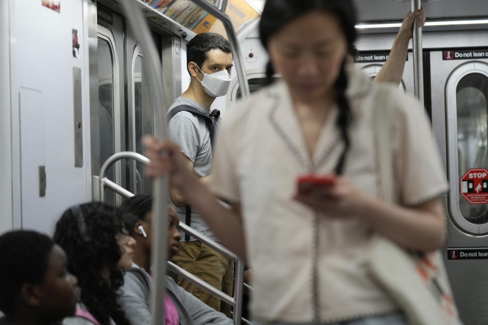 Commuters, one wearing a mask, ride the subway in New York, Friday, June 14, 2024. New York Gov. Kathy Hochul says she is considering a ban on face masks in the New York City subway system, following what she described as concerns over people shielding their identities while committing antisemitic acts. (AP Photo/Seth Wenig)