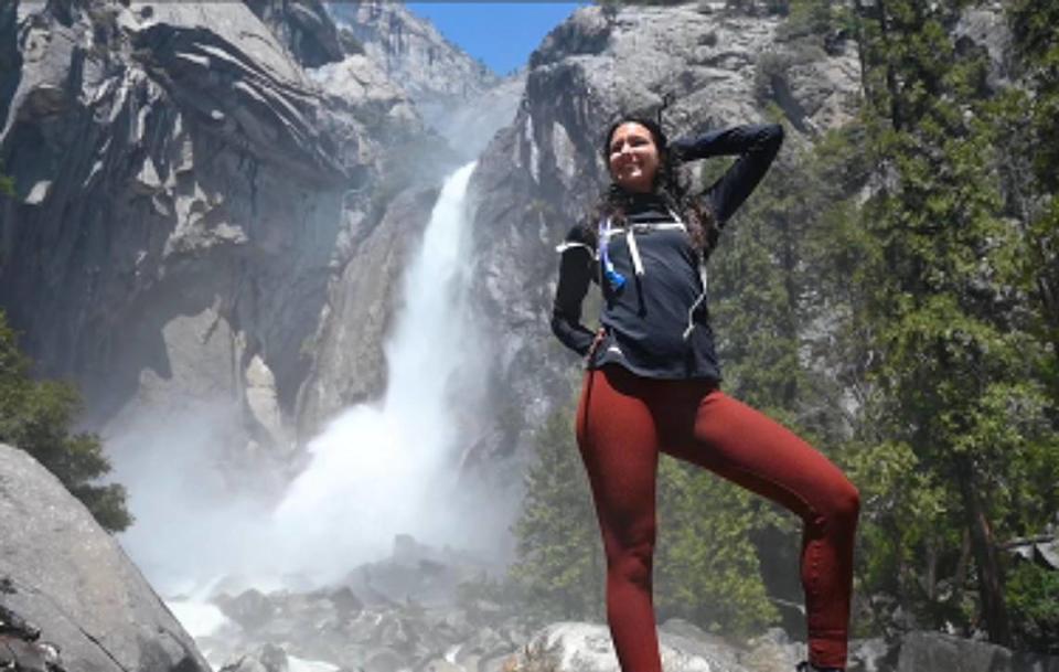 Victoria Mansa, visting the park with the group LA Women of Wellness, poses for a photo in the freezing spray of Lower Yosemite Fall Friday, April 28, 2023 in Yosemite Valley.