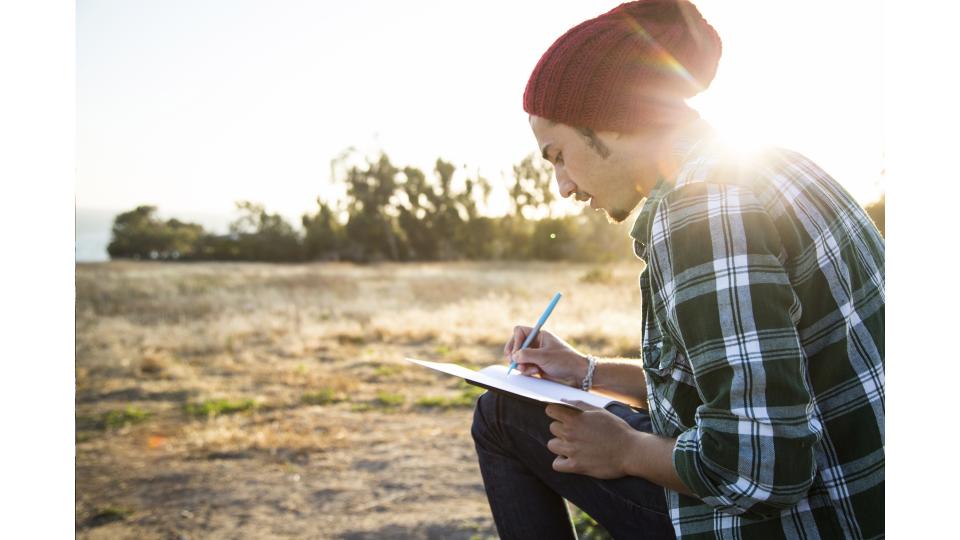 A man nature journaling at sunset