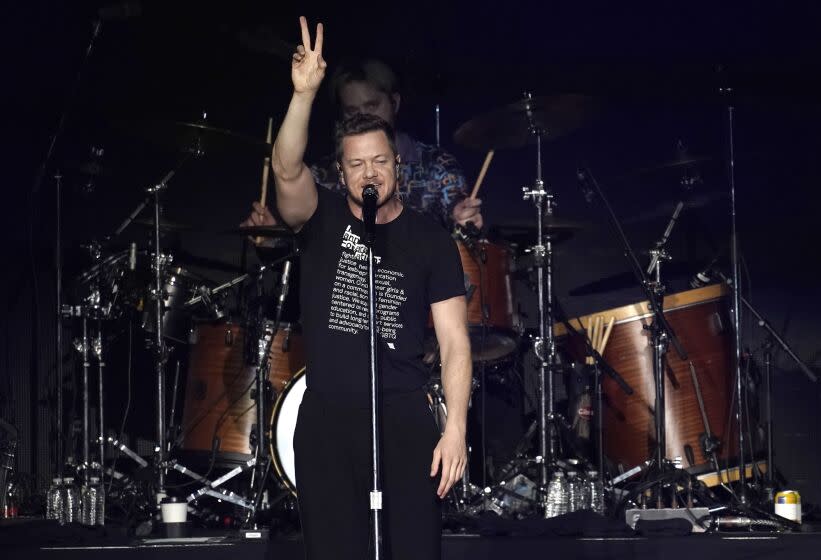 A man making a peace sign in the air while standing in front of a microphone on a stage