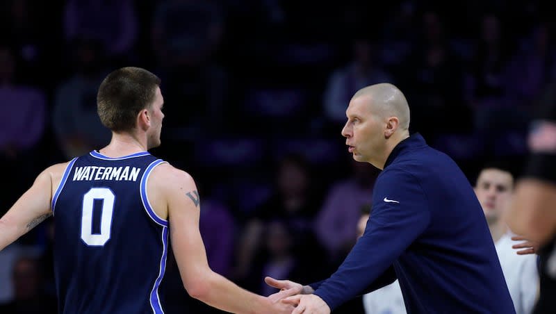 BYU coach Mark Pope, right, reacts greets forward Noah Waterman as he heads to the bench during game against Kansas State, Saturday, Feb. 24, 2024, in Manhattan, Kan.