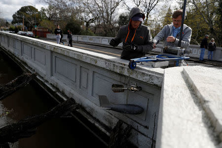 Technicians with the Santa Clara Valley Water District lower an instrument to collect flow measurements of Coyote Creek a day after neighborhoods flooded and prompted evacuation of 14,000 in San Jose, California, U.S., February 22, 2017. REUTERS/Stephen Lam