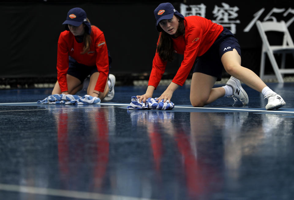 Ball girls attempt to dry their court after rain stopped play during second round matches at the Australian Open tennis championships in Melbourne, Australia, Thursday, Jan. 17, 2019. (AP Photo/Mark Schiefelbein)