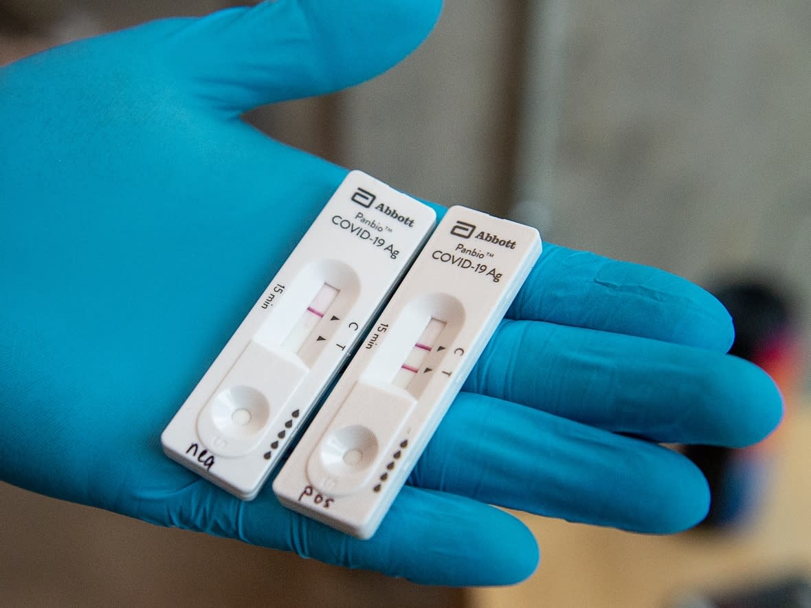 A negative and a positive rapid test are seen being held by a gloved professional. Nova Scotia is reporting 502 new lab-confirmed cases of COVID-19 on Saturday. (Andrew Vaughan/The Canadian Press - image credit)