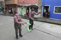 Los miembros de la compañía "Circo Encuentro" realizan un acto de malabarismo para los residentes, mientras esperan que una caldera de sopa se cocine con alimentos donados en Bogotá, Colombia, el sábado 4 de julio de 2020. El grupo prepara lo que llaman una "sopita de murciélago" en un vecindario seleccionado para residentes que han sido afectados económicamente por los cierres relacionados con el COVID-19. (Foto AP/Fernando Vergara)