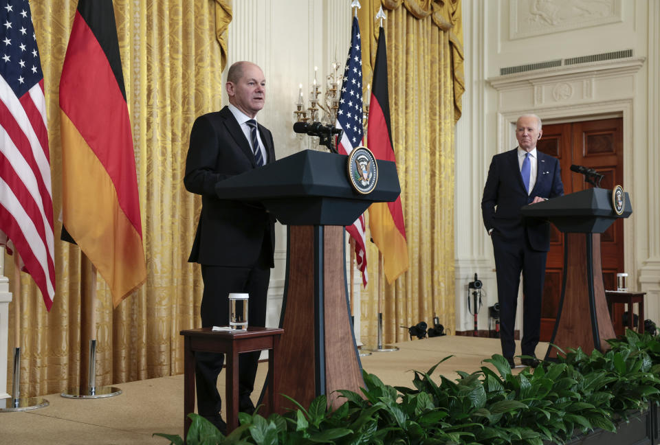 German Chancellor Olaf Scholz and President Biden stand at separate podiums during a joint news conference.