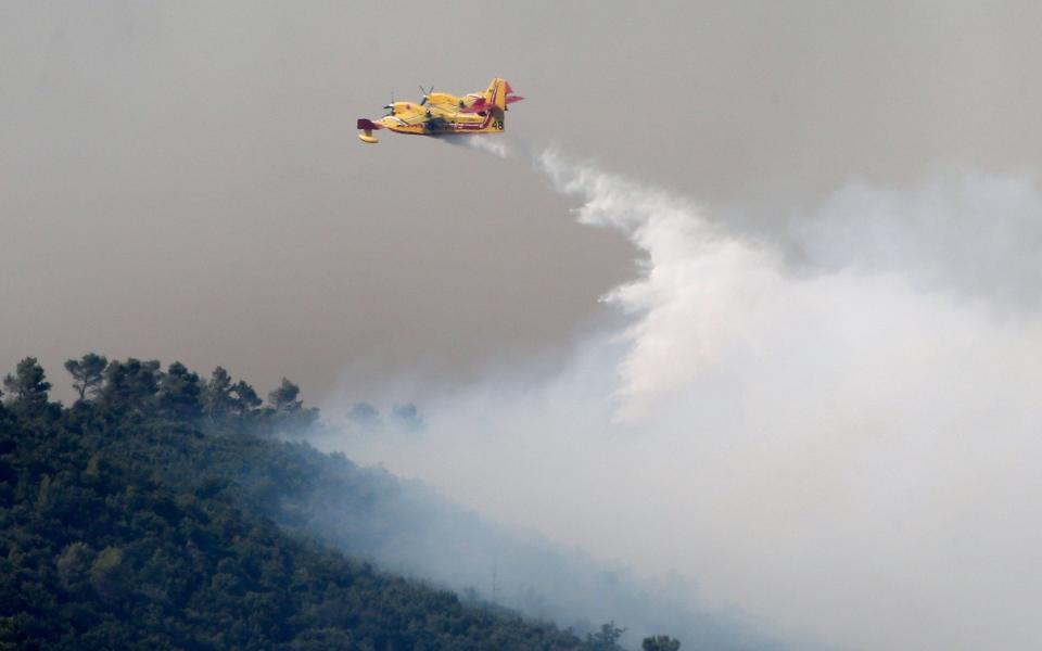 Smoke fills the sky as a Canadair firefighting plane releases water to extinguish a wildfire near Seillons - Credit: JEAN-PAUL PELISSIER/REUTERS