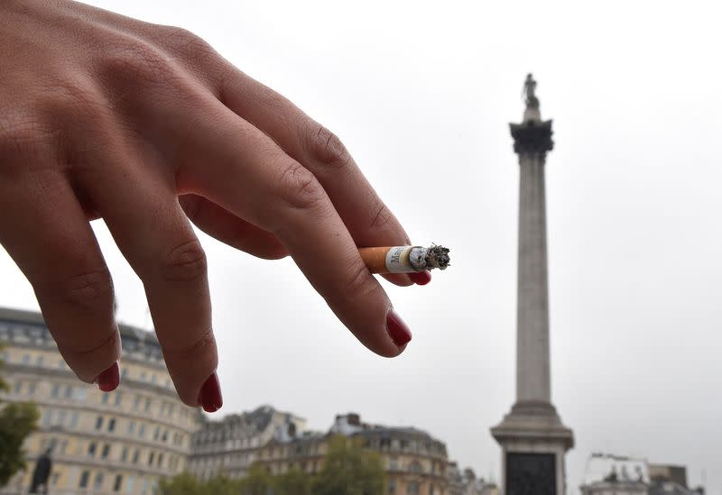 FILE PHOTO: A woman holds her cigarette as she smokes in Trafalgar Square in central London