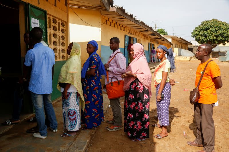 People wait in front of a polling station during the legislative election in Abidjan