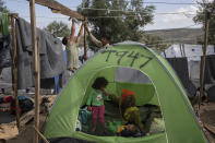 In this Saturday Oct. 5, 2019 photo, Afghan men prepare their tent after a rainfall, in a makeshift refugee and migrant camp on the fringes of the overcrowded Moria camp on the Greek island of Lesbos. Greece's conservative government announced Wednesday Nov. 20, 2019, plans to overhaul the country's migration management system, and replacing existing camps on the islands with detention facilities and moving and 20,000 asylum seekers to the mainland over the next few weeks. (AP Photo/Petros Giannakouris)