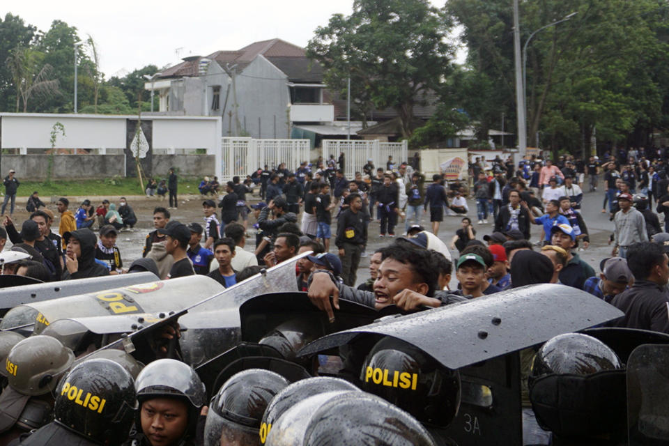 Riot police officers block soccer supporters outside Jatidiri Stadium in Semarang, Central Java, Indonesia, Friday, Feb. 17, 2023. Indonesian police fired tear gas to disperse fans who were trying to force their way into a match that was held without spectators, months after the use of tear gas in another stadium in East Java caused one of the world's worst sporting disasters. (AP Photo/Adhik Kurniawan)