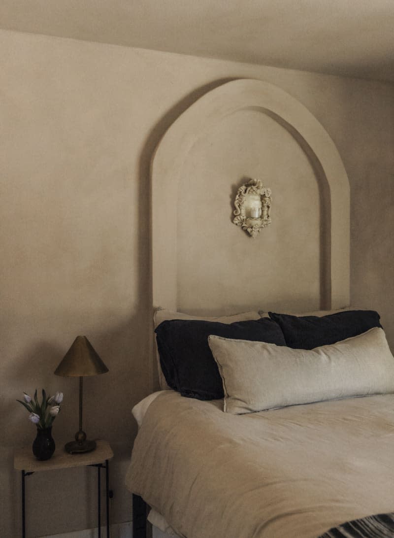 Bedroom with warm neutral textured walls and relief arch over bed