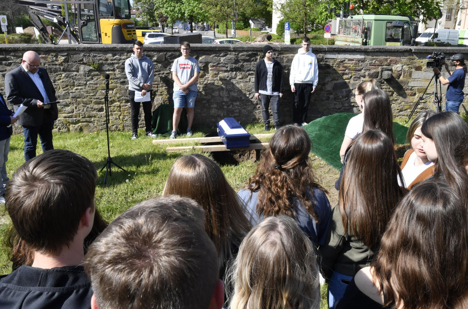 Pupils of the Johannes-Sturmius-Gymnasium say goodbye to the coffin with the bones of a school skeleton at the cemetery, where they are being buried, in Schleiden, Germany, May 11, 2022. The real skeleton of an unknown woman, christened Anh Bian by the students, had served as a visual object for the students in biology classes since 1952. It has since been replaced by a plastic model. (Roberto Pfeil/dpa via AP)