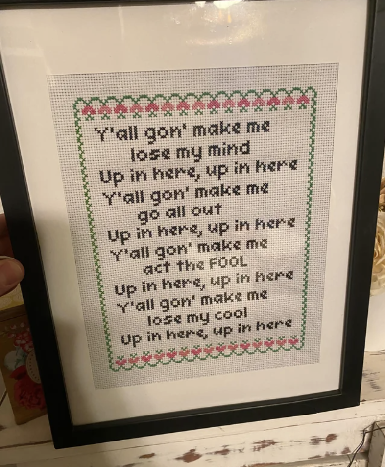 A framed sign with a "homey," old-fashioned style, with lyrics from DMX's "Party Up," including "Y'all gon' make me lose my mind / Up in here, up in here / Y'all gon' make me go all out / Up in here, up in here"