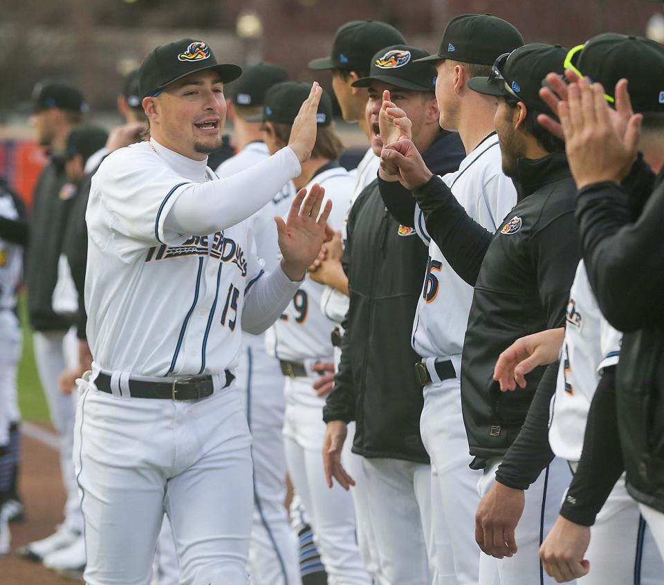 Akron RubberDucks third baseman Raynel Delgado slaps hands with teammates during introductions, Thursday, April 6, 2023.