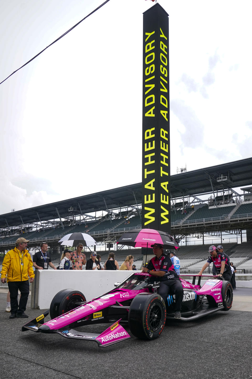 The team of Helio Castroneves, of Brazil, pushes the car back to the garage as rain halted qualifications for the Indianapolis 500 auto race at Indianapolis Motor Speedway in Indianapolis, Saturday, May 21, 2022. (AP Photo/Michael Conroy)