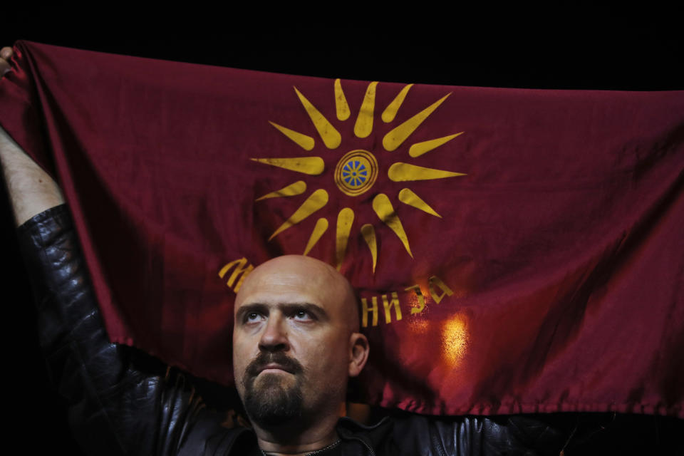 A supporter of a movement for voters to boycott the referendum, holds an old Republic of Macedonia flag during celebrations in central Skopje, Macedonia, after election officials gave low turnout figures, Sunday, Sept. 30, 2018. The flag was replaced in 1995 after a one-year economic blockade imposed by Greece in order to force the country to remove the Vergina Sun, a symbol from the gravesite of the ancient Kings of Macedon from the flag, as Greece considered it a Greek symbol. The crucial referendum on accepting a deal with Greece to change the country's name to North Macedonia to pave the way for NATO membership attracted tepid voter participation Sunday, a blow to Prime Minister Zoran Zaev's hopes for a strong message of support. (AP Photo/Thanassis Stavrakis)
